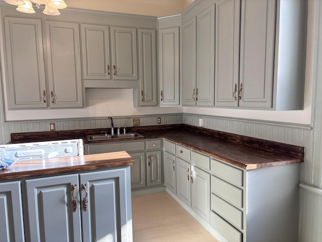 kitchen featuring gray cabinets, sink, and wooden counters