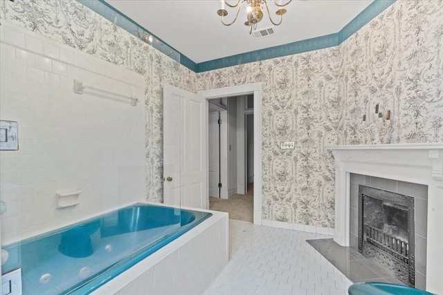 bathroom with a chandelier, tiled bath, tile patterned floors, and a tiled fireplace