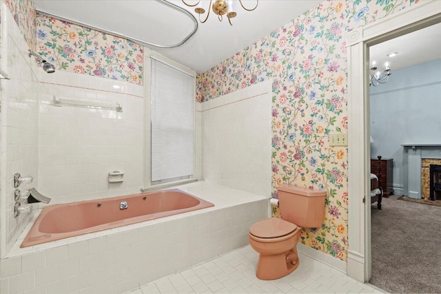 bathroom with a chandelier, tiled shower / bath combo, and toilet