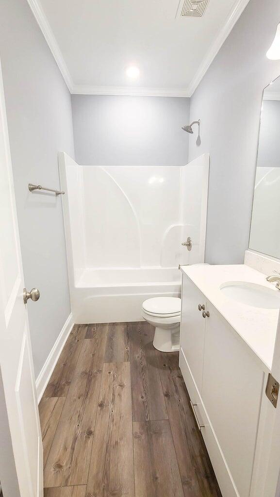 full bathroom featuring crown molding, hardwood / wood-style flooring,  shower combination, vanity, and toilet