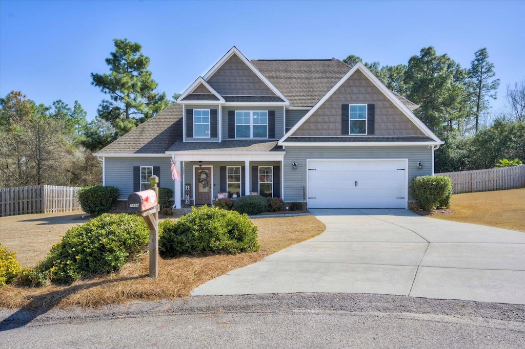 craftsman inspired home featuring an attached garage, fence, a porch, and concrete driveway