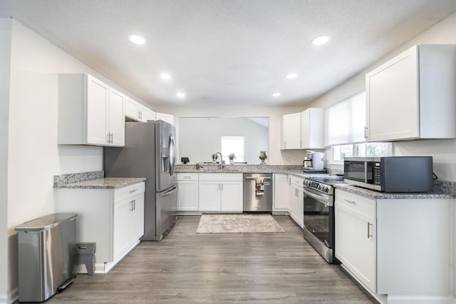 kitchen featuring light stone countertops, white cabinetry, sink, dark wood-type flooring, and appliances with stainless steel finishes