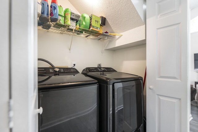 laundry area with a textured ceiling, washing machine and dryer, and wood-type flooring