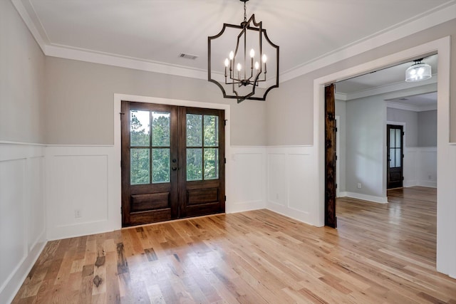 110 Collin Reeds Rd, North Augusta, SC 29860 - entrance foyer with french doors, a wainscoted wall, a decorative wall, light wood-style flooring, and a chandelier