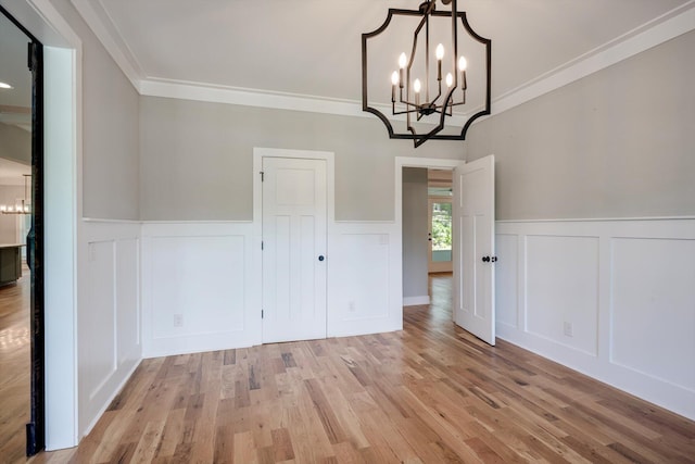 110 Collin Reeds Rd, North Augusta, SC 29860 - unfurnished dining area with a chandelier, a decorative wall, wainscoting, light wood finished floors, and crown molding