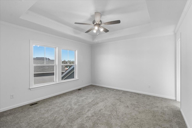 carpeted spare room featuring ornamental molding, ceiling fan, and a tray ceiling