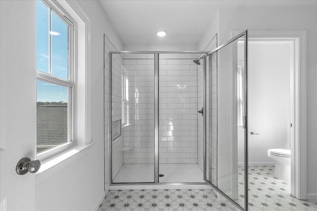 bathroom featuring a shower with shower door and toilet