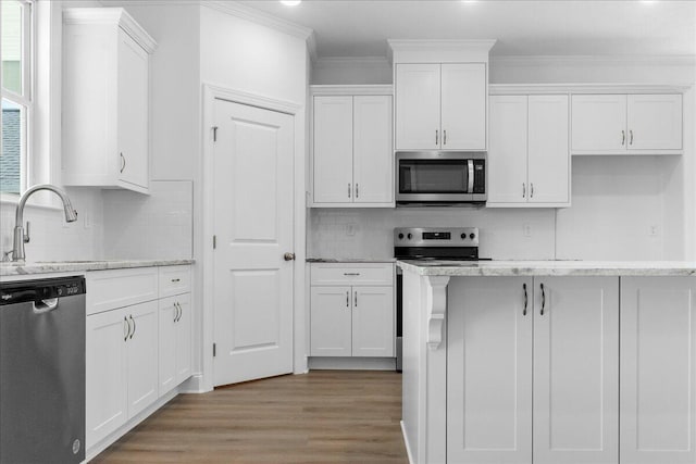 kitchen with sink, white cabinetry, ornamental molding, appliances with stainless steel finishes, and light stone countertops