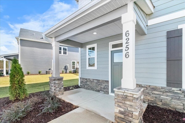 view of exterior entry with a lawn and covered porch