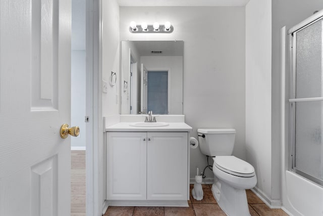 full bath featuring baseboards, bath / shower combo with glass door, toilet, vanity, and tile patterned floors