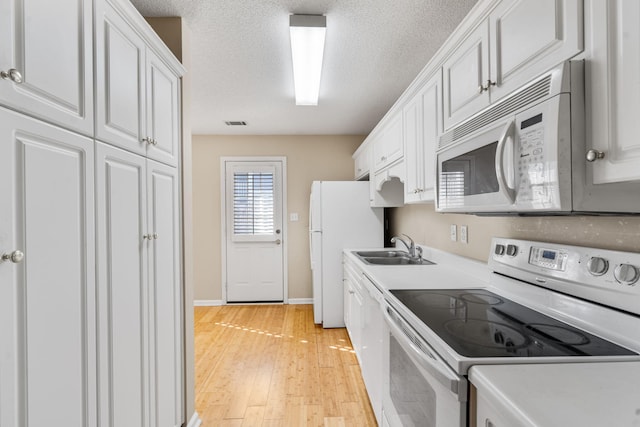 kitchen with white cabinetry, a sink, light countertops, light wood-style floors, and white appliances