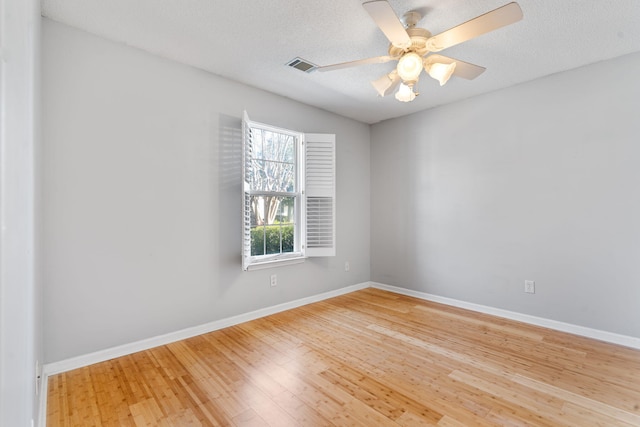 empty room with baseboards, a ceiling fan, wood finished floors, and a textured ceiling