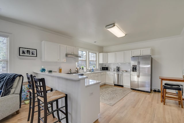 1321 Holden St, Augusta, GA 30904 - kitchen with stainless steel appliances, a breakfast bar, a peninsula, white cabinets, and decorative backsplash