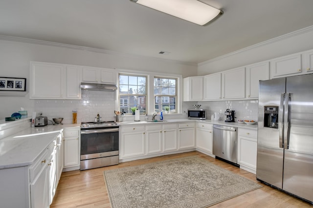 1321 Holden St, Augusta, GA 30904 - kitchen with appliances with stainless steel finishes, backsplash, crown molding, white cabinets, and light wood-style flooring