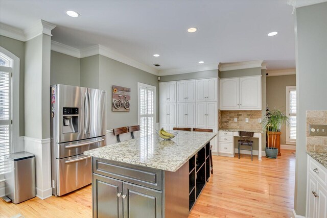 5407 Kiokee Ridge Rd, Evans, GA 30809 - kitchen with decorative backsplash, light stone countertops, white cabinetry, stainless steel fridge with ice dispenser, and light wood-style flooring
