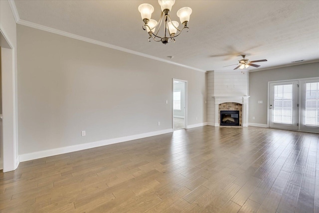 unfurnished living room with a large fireplace, crown molding, ceiling fan with notable chandelier, and hardwood / wood-style floors