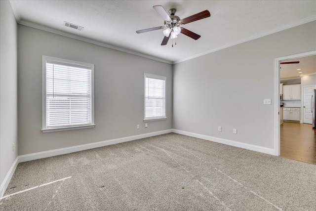 spare room with ceiling fan, plenty of natural light, carpet, and ornamental molding