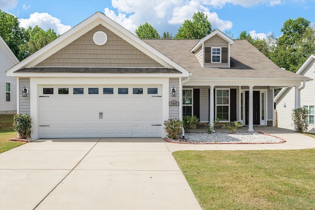 view of front of house with a garage, covered porch, and a front lawn