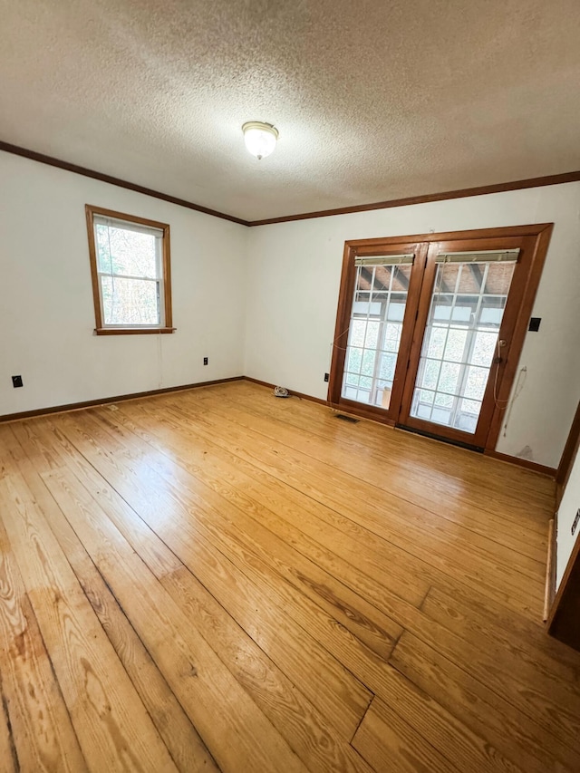 empty room featuring wood-type flooring, a textured ceiling, and a wealth of natural light