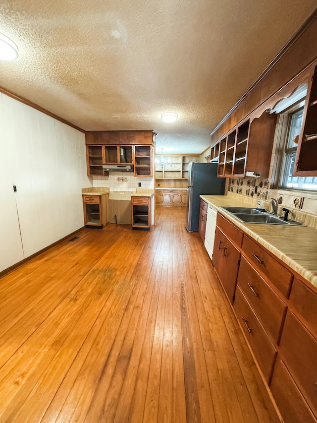 kitchen featuring white dishwasher, sink, light hardwood / wood-style flooring, stainless steel fridge, and a textured ceiling