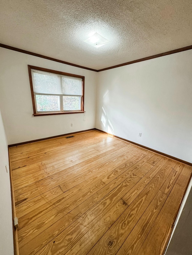 spare room with ornamental molding, a textured ceiling, and light hardwood / wood-style flooring