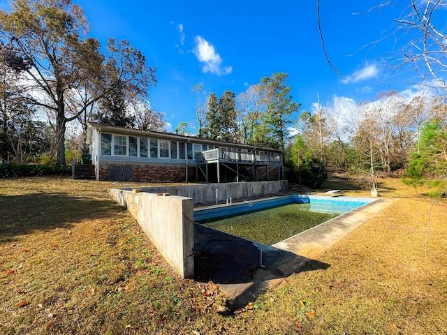 rear view of property featuring a pool side deck and a lawn