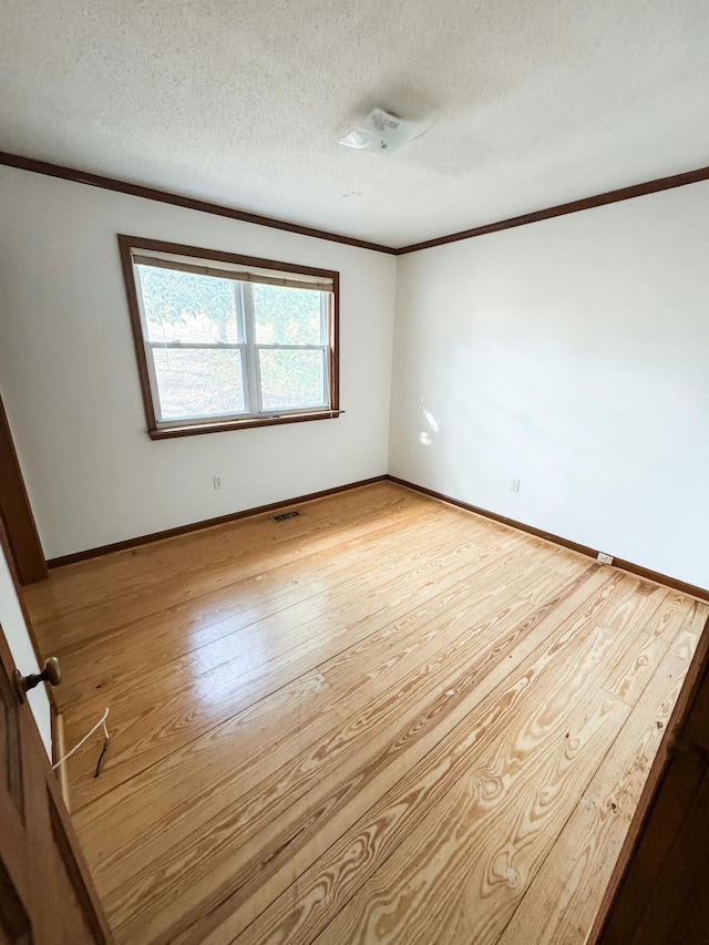 empty room with crown molding, light hardwood / wood-style floors, and a textured ceiling