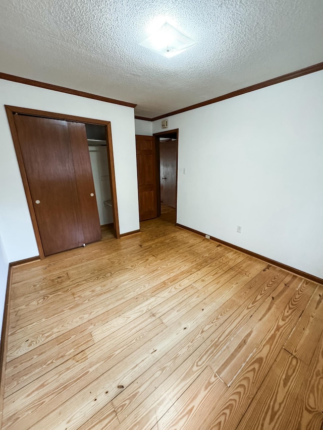 unfurnished bedroom featuring a textured ceiling, light wood-type flooring, a closet, and crown molding