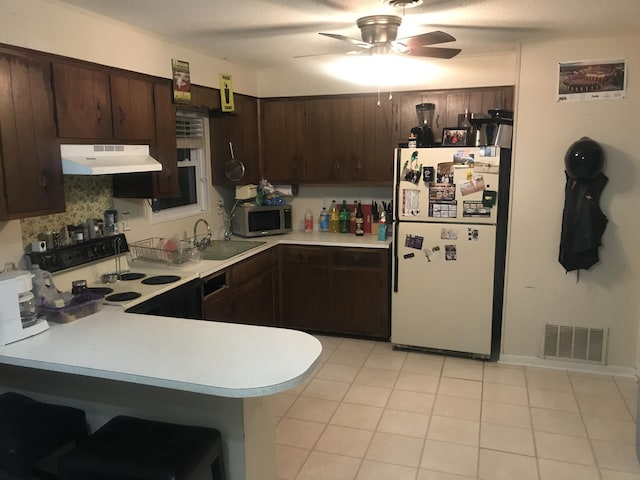 kitchen featuring kitchen peninsula, white appliances, dark brown cabinetry, ceiling fan, and sink