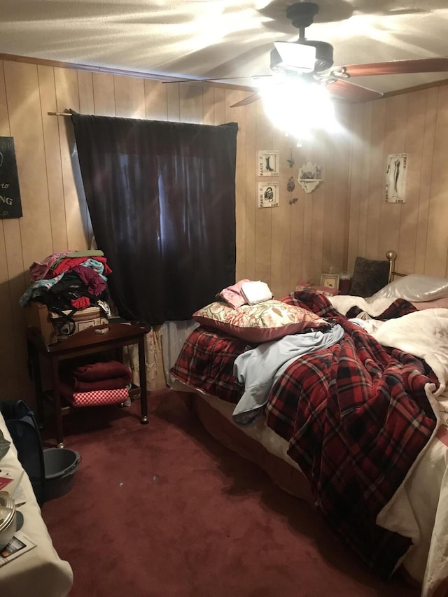 bedroom featuring ceiling fan, wooden walls, and carpet floors