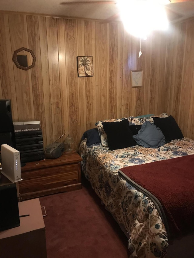 bedroom featuring wooden walls and dark carpet