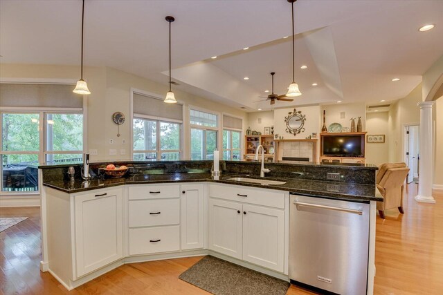 kitchen featuring white cabinetry, dishwasher, hanging light fixtures, decorative columns, and dark stone counters