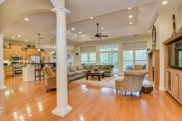 living room with ceiling fan, light wood-type flooring, and ornate columns