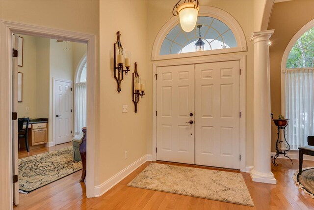 foyer with light hardwood / wood-style floors, a high ceiling, and decorative columns