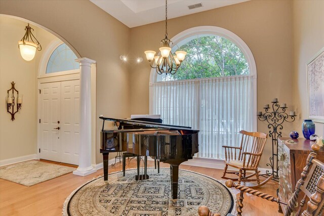 entrance foyer with a notable chandelier, wood-type flooring, and ornate columns