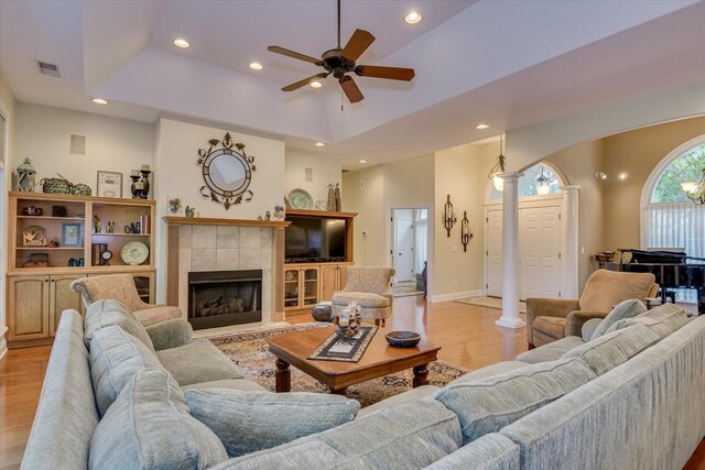 living room with a raised ceiling, decorative columns, and light hardwood / wood-style floors