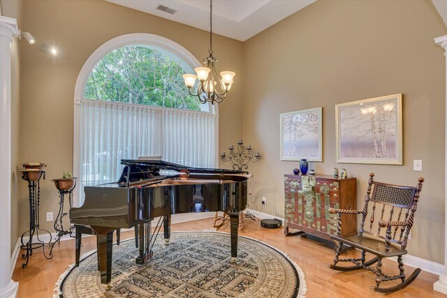 misc room with hardwood / wood-style floors, a notable chandelier, and decorative columns