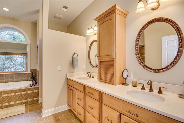 bathroom with tile patterned floors, vanity, and a relaxing tiled tub