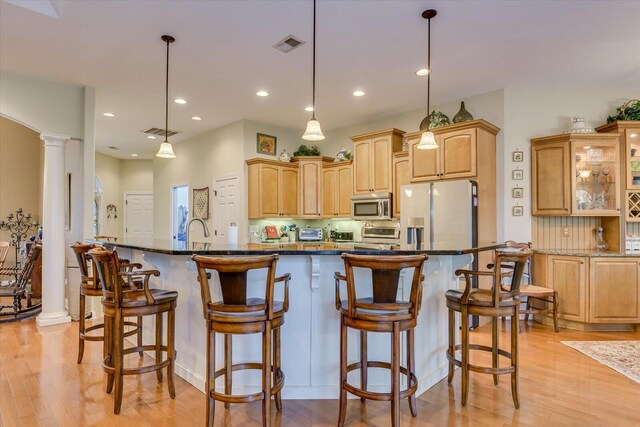 kitchen with pendant lighting, a kitchen breakfast bar, white fridge with ice dispenser, tasteful backsplash, and decorative columns