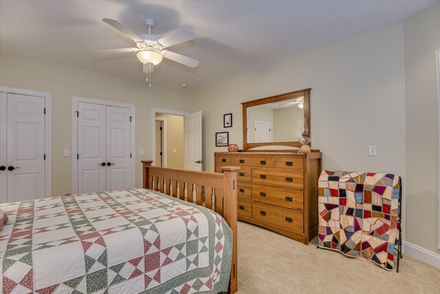 carpeted bedroom with ceiling fan and two closets