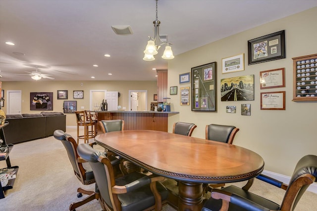 carpeted dining area featuring ceiling fan with notable chandelier