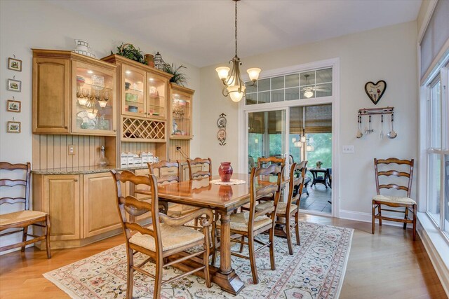 dining area with light wood-type flooring and an inviting chandelier