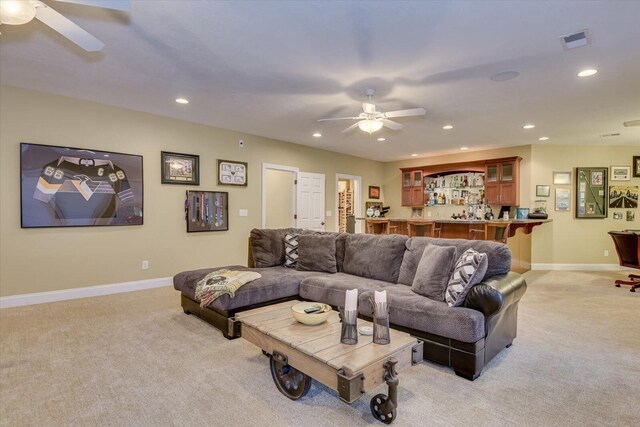 living room with bar area, ceiling fan, and light carpet