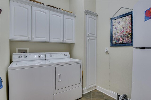 washroom featuring cabinets, dark tile patterned floors, and washer and dryer