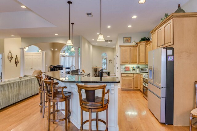 kitchen featuring decorative columns, light brown cabinets, decorative light fixtures, and stainless steel refrigerator with ice dispenser