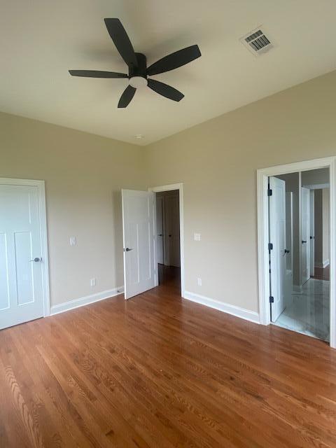 2016 Elite Ct, Hephzibah, GA 30815 - unfurnished bedroom with wood finished floors, baseboards, ceiling fan, and ensuite bathroom