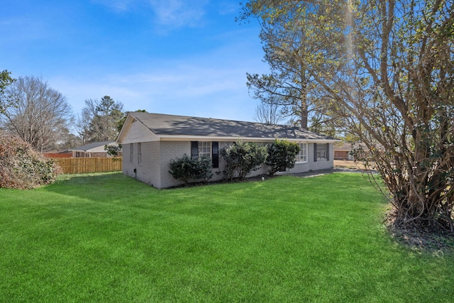 rear view of house with brick siding, a yard, and fence