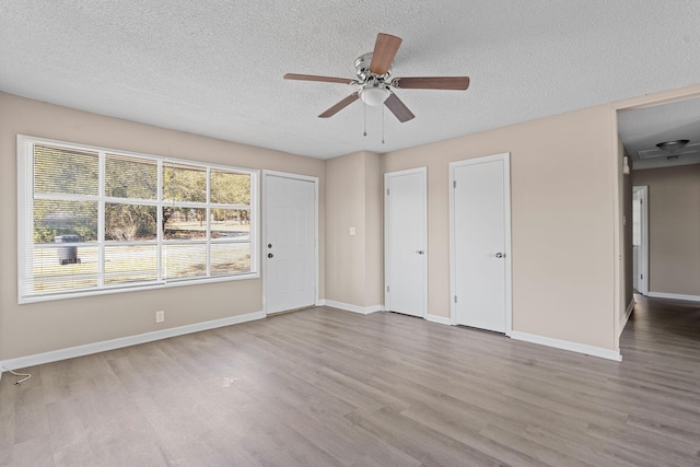 interior space featuring a textured ceiling, wood finished floors, and baseboards