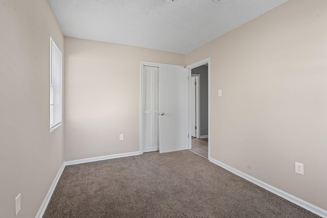 carpeted spare room with a textured ceiling and baseboards