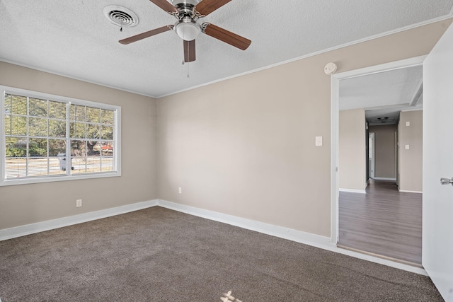 empty room featuring baseboards, visible vents, ornamental molding, dark colored carpet, and a textured ceiling